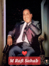 a man in a suit and tie sits in a chair with a red heart and the name m rafi sahab