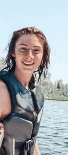 a young woman wearing a life jacket is smiling while standing on a boat .