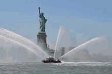 the statue of liberty is being sprayed with water by a boat