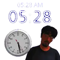 a man with glasses stands next to a clock that says 0528 am