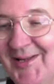 a close up of a man wearing glasses and making a funny face .