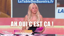 a woman sitting at a table with the words ah oui c'est ca written on the screen