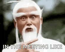 a man with a beard and white hair is pointing at the camera .