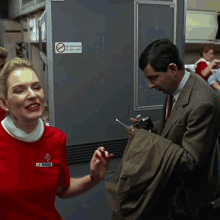 a woman in a red dress stands next to a man in a suit in front of a sign that says no smoking in this area