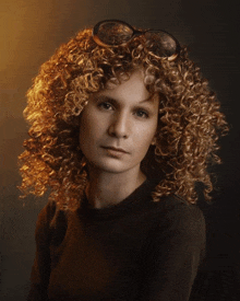 a woman with curly hair wearing glasses and a black sweater