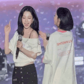 a woman wearing a smtown live t-shirt stands next to another woman