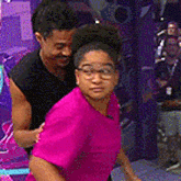 a man is carrying a woman in a pink shirt on his shoulders .