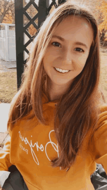 a woman wearing a yellow sweatshirt with the word " weijto " on it smiles for the camera