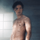 a shirtless man is standing in front of a window .