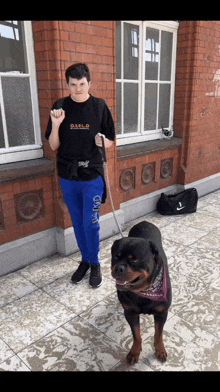 a man wearing a diablo t-shirt is walking a dog on a leash