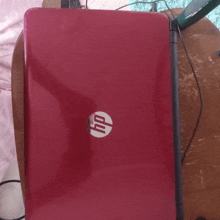 a red hp laptop is open and sitting on a wooden table