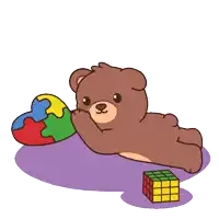 a brown teddy bear is laying on the floor holding a heart shaped puzzle piece and a rubik 's cube