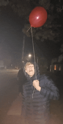 a man is holding a red balloon in his hand