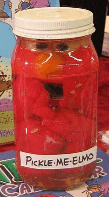 a jar of pickle me elmo sits on a red table