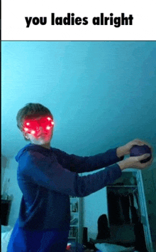 a boy with red eyes is holding a purple ball in his hands .