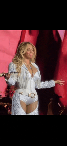 a woman in a white outfit is singing into a microphone on a stage .