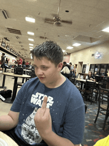 a boy wearing a star wars t-shirt giving the middle finger