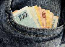 a 100 bill is sticking out of a jeans pocket