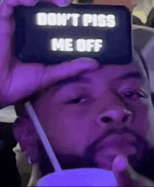 a man is holding a cell phone with the words `` don 't piss me off '' on it .