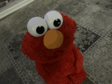 elmo from sesame street is sitting on a rug on the floor