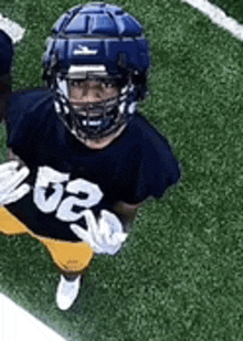 a young football player wearing a helmet and gloves is standing on a field .