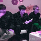 a group of young men are sitting on a couch and playing a video game .
