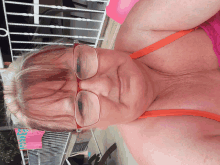 an older woman wearing glasses and an orange bikini top looks down