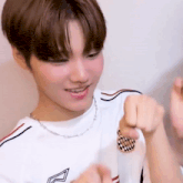 a young boy wearing a white t-shirt and a necklace is giving a thumbs up .