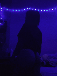 a person is sitting in a dark room with purple lights hanging from the ceiling