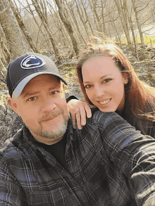 a man wearing a penn state hat is posing for a picture with his wife