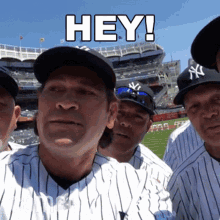 a group of baseball players are posing for a picture and one of them is wearing a new york yankees hat