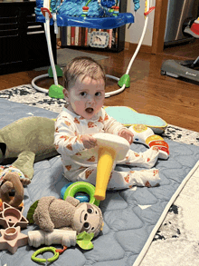 a baby is sitting on a mat playing with toys and a baby trend treadmill is in the background