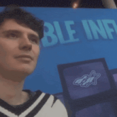 a man stands in front of a large blue sign that says ble influx