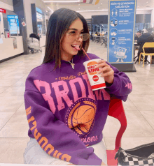 a woman in a purple sweatshirt drinking a burger king drink