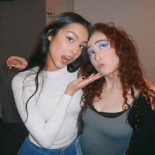 two girls are posing for a picture and one has purple eye makeup