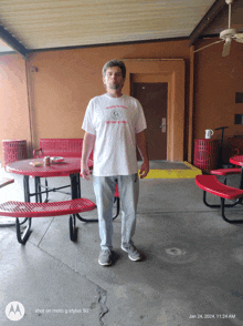 a man wearing a white shirt that says nothing to lose is standing in a picnic area