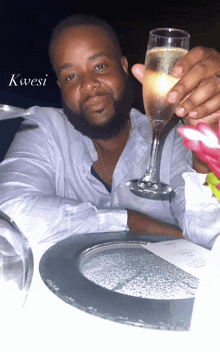 a man is holding a glass of champagne with the word kwesi written on the bottom