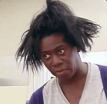 a woman with messy hair is making a funny face and looking at the camera .