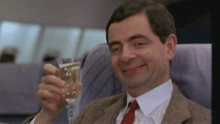 a man in a suit is holding a glass of champagne