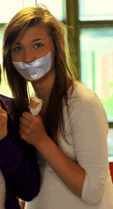 a girl with duct tape on her mouth is holding a ice cream cone