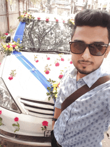 a man wearing sunglasses is standing in front of a white car with flowers on it