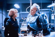 a woman in a police uniform stands next to a man in a robotic suit