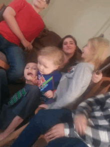 a group of people sitting on a couch with a baby wearing a shirt that says ' hulk ' on it