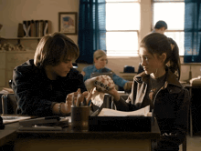a boy and a girl sit at a desk in a classroom looking at a soccer ball