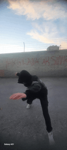 a person is standing in front of a wall with graffiti on it that says " vargilanacaksin "