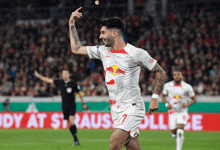 a soccer player wearing a white jersey with a red bull on it