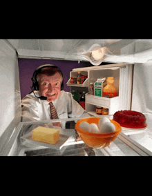 a man wearing headphones is looking into a refrigerator filled with eggs and butter