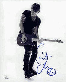 a man is holding a guitar in a black and white photo and has signed it .