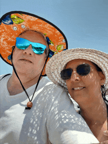 a man and woman wearing hats and sunglasses pose for a photo