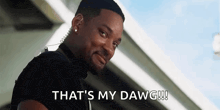 a man in a black shirt is standing in front of a building and says `` that 's my dawg ! ''